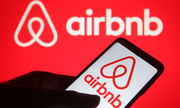 An Airbnb logo is displayed on a smartphone and a PC screen.