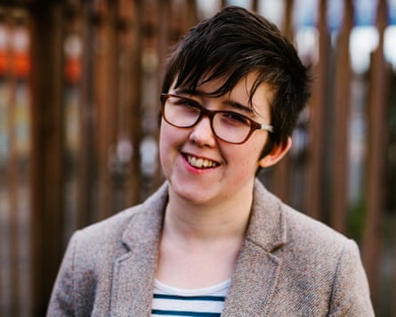 Lyra McKee smiles and wears glasses and a stripy T-shirt and jacket