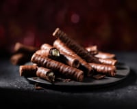 Chocolate wafer batons piled on a plate, one broken open revealing peppermint filling.