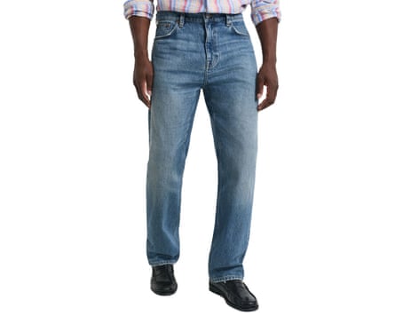 A cropped at waist image of a model wearing Gant straight fit mid blue jeans.