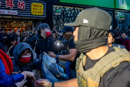 a masked man holds a taser