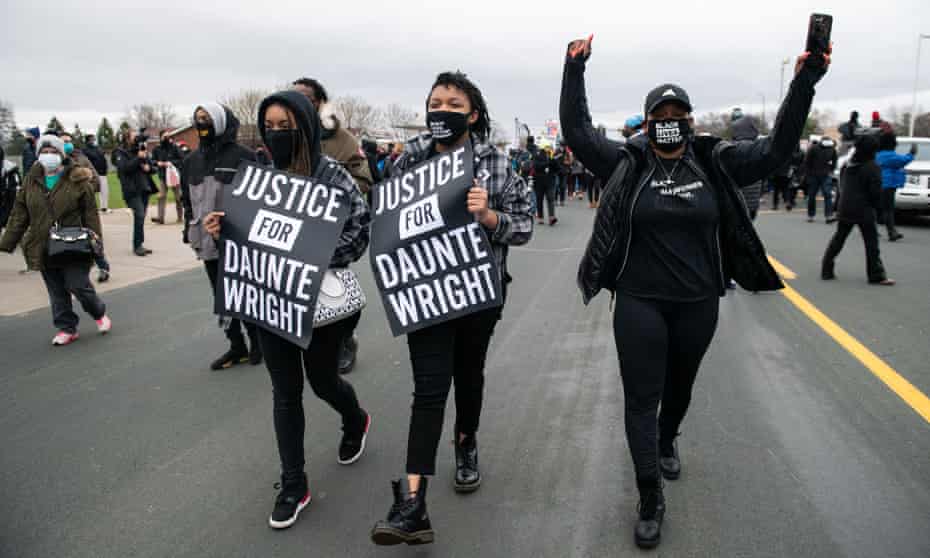 Protesters carrying ‘Justice for Daunte Wright’ signs march near the Brooklyn Center police department in Minnesota on 13 April. 