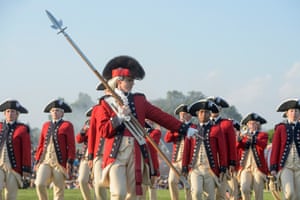 Soldiers in traditional red jackets and cream breeches march in a field