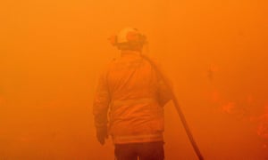A firefighter conducts back-burning measures to secure residential areas from encroaching bushfires in the Central Coast,