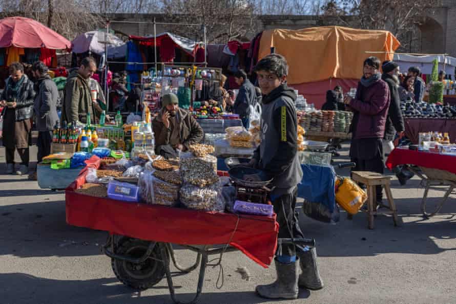 a boy with a wheelbarrow of nuts and seeds for sale in a market