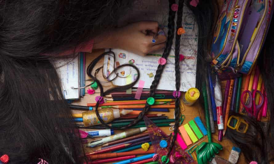 Antonella Bordon shot from above doing school work with her braided hair mixed up with her pens and stationery