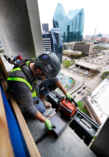 a construction worker lines up the fitting for a window pane in a skyscraper