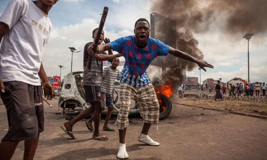 Demonstrators gather in front of a burning car during an opposition rally in Kinshasa that called on the long-serving president, Joseph Kabila, to step down.