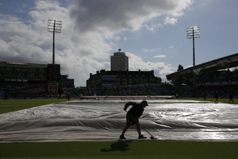 Ground staff work on the wicket as the rain stops and the sun comes out.