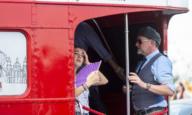 A woman uses a fan to keep cool on a bus on Westminster Bridge in London.