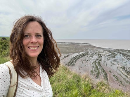 Rhiannon Batten on the path between Doniford and St Audries Bay. Young woman smiling with ridged rock formations and sea in background