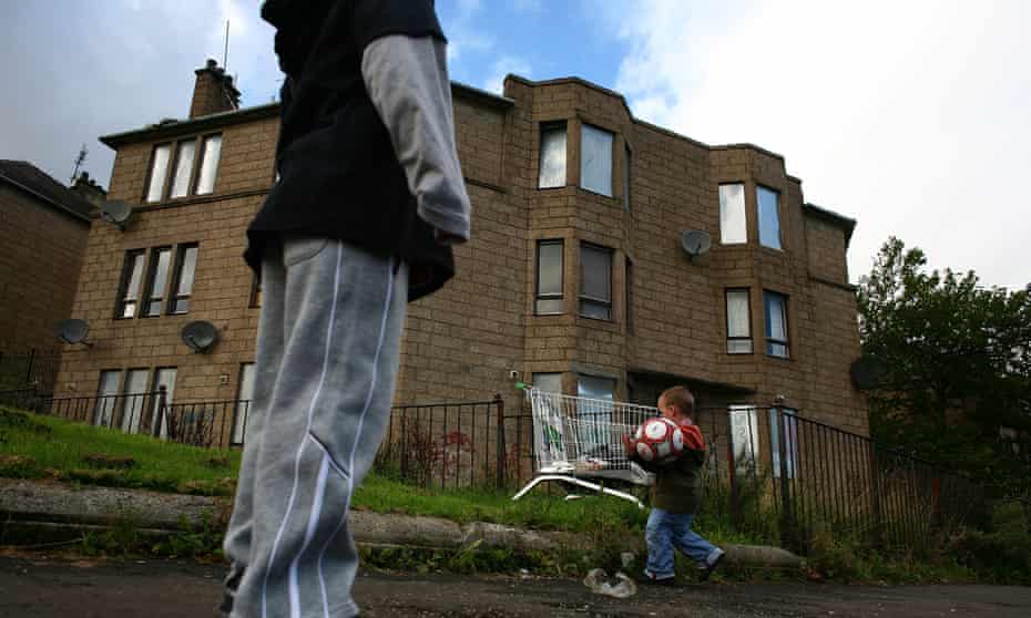 Boys play in front of a house with boarded up windows in Scotland
