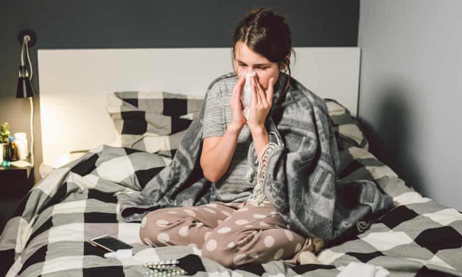 sick woman with runny nose sitting in bed