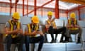 Labourers in hi-viz jackets using their phones at a warehouse