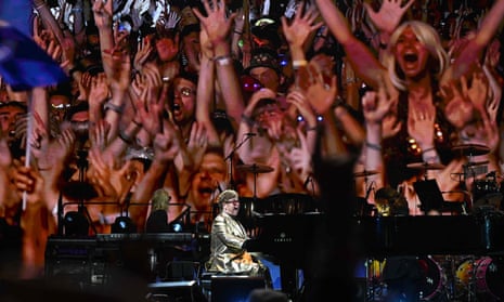 Can you feel the love … Elton John plays with the crowd projected behind him.