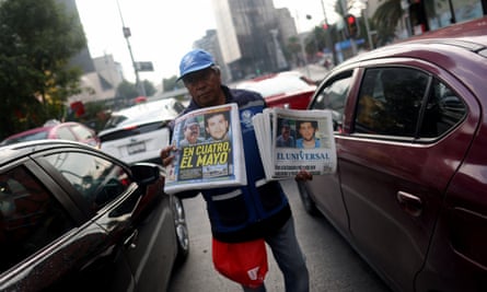 A news vendor in the traffic selling papers reporting the arrests of El Mayo and the son of El Chapo.