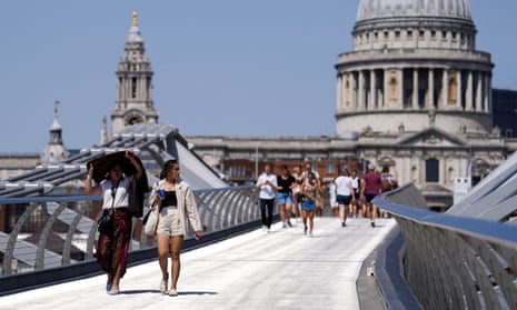 People cover themselves from the sun at Millennium Bridge during a heatwave, in London, Britain, July 18, 2022. 