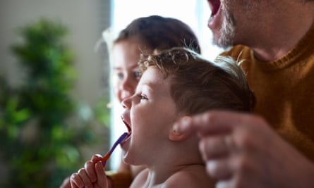 Man showing children how to brush teeth