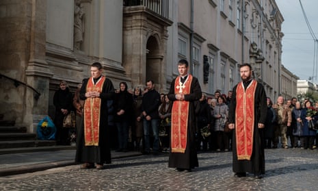 Tres sacerdotes vestidos con túnicas negras y rojas caminando uno al lado del otro al frente de una procesión