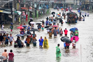 People walk through a flooded street in knee-high water