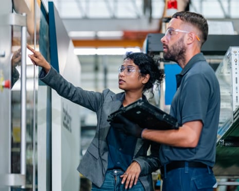 A manager and engineer examine a factory control panel