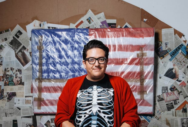 A man standing in front of an artwork of the American flag.
