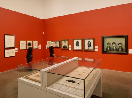 Gallery visitors view framed L.S. Lowry portraits on a red wall near a display case