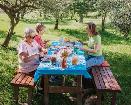 People having breakfast outside on wooden table in an orchard