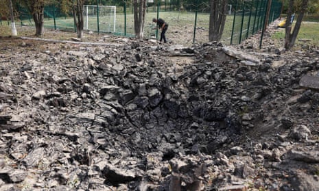 A Ukrainian police officer inspects a large dark crater near a school after an airstrike in the Donetsk region on Friday