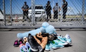 Security personal stand before shoes and toys left at the Tornillo Port of Entry where minors crossing the border without proper papers have been housed after being separated from adults
