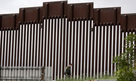 A border patrol agent walks along a border wall separating Tijuana, Mexico, from San Diego, on Wednesday.