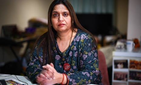 Seema Misra, sitting at a table with hands clasped, wearing a badge reading 'The great post office scandal'