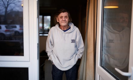Phil Baraclough stands in the door of his Manchester flat