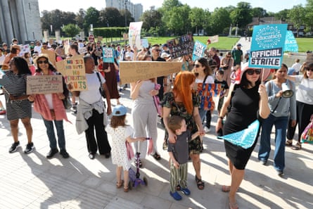 Protesters with mostly homemade placards cast long shadows in the sun