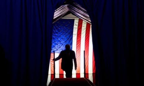 Silhouette of a man against an illuminated American flag.