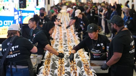 People successful matching achromatic T-shirts connected either broadside of a agelong array statement up cheesesteaks successful rows