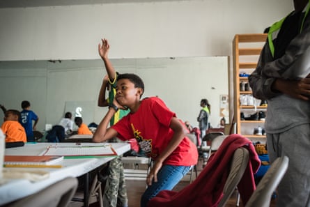 boy smiles at table as another child raises hand