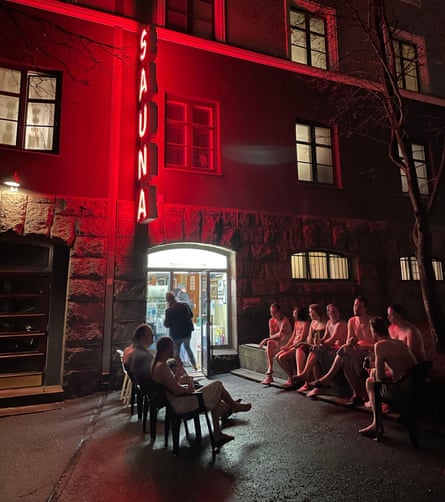 People in swimwear sitting on chairs outside.