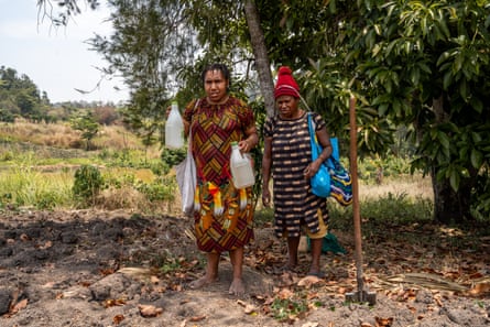 Two women carrying water jugs after walking from a village well