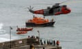 People wave on a harbour as RNLI craft and a Royal Navy rescue helicopter pass by in Newquay, Cornwall.