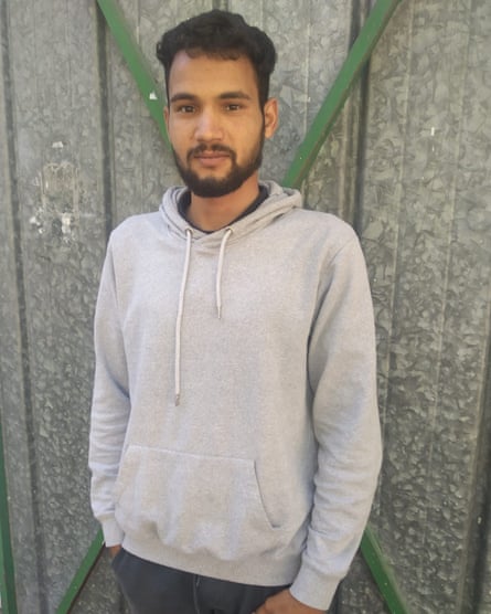 Rafie Nadi posing in a grey hoodie against an industrial gateway
