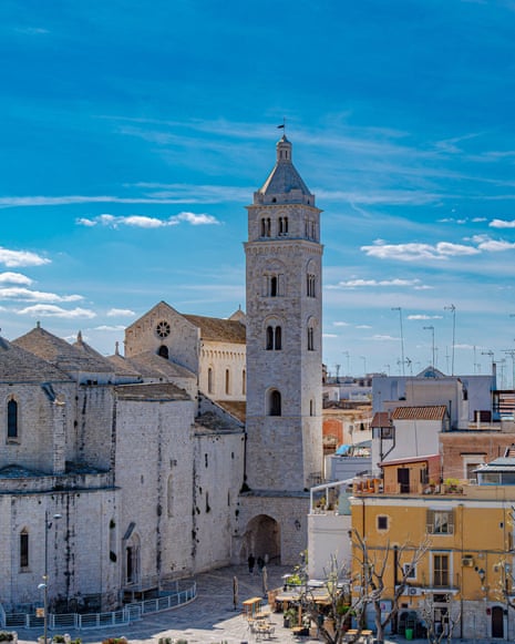 Barletta Cathedral's stone bell tower rises over the town under a bright blue sky, in northern Puglia, Italy.