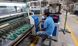 A worker is waiting for products to arrive on a production line at the Aqualite footwear factory in Bahadurgarh in the northern Indian state of Haryana.