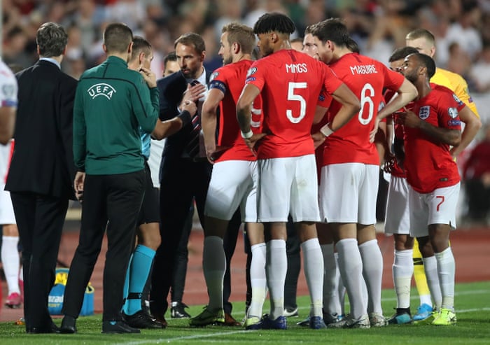 The England players and manager Gareth Southgate speak to referee Ivan Bebek as the match is stopped during the first half.