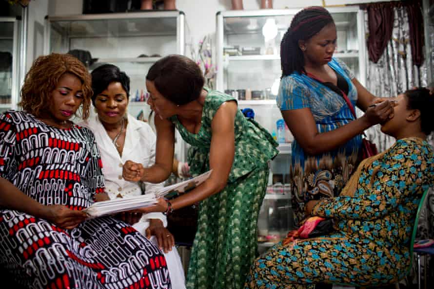 An apprentice hairdresser at the Jumelle salon in Conakry shows a client different family planning methods