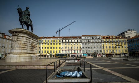 A homeless person sleeps covered with a blanket at Figueira square in Lisbon.