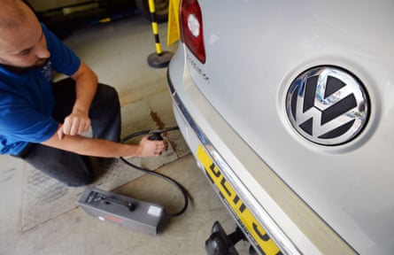 Man holds device near the exhaust of a car.