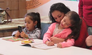 Yeimi kisses her five-year-old daughter Michelle while her three-year-old daughter Victoria sits next to her, at a press conference at Annunciation House in El Paso, Texas.