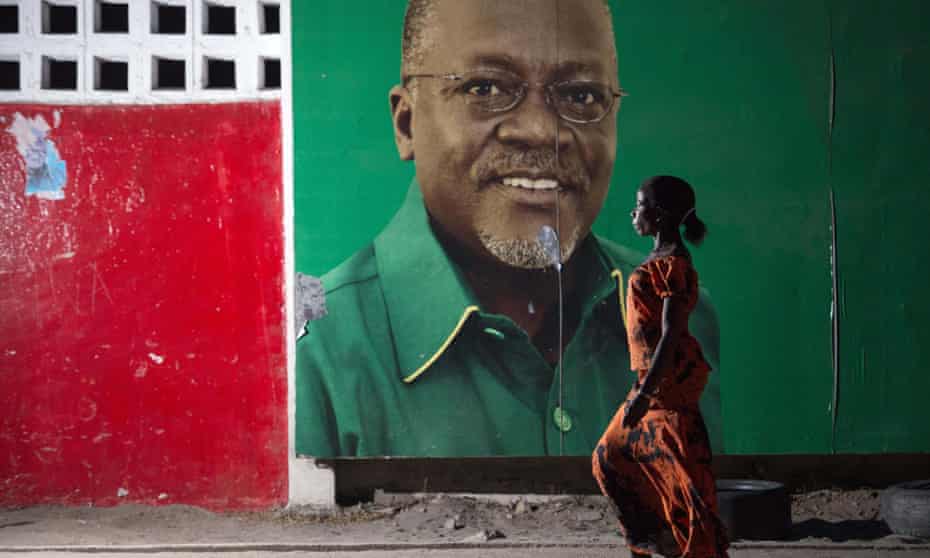 A woman walks past a billboard bearing a picture of Tanzanian president John Magufuli