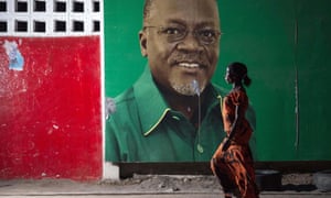 A woman walks past an election billboard after John Magufuli (pictured on billboard) was named president-elect